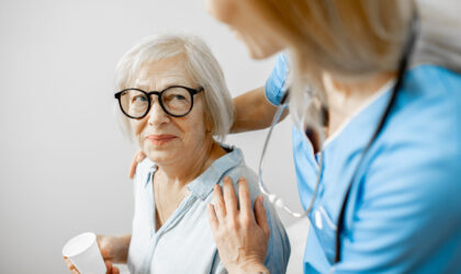 Nurse taking care of senior woman, hugging her shoulders in the clinic or home for elderly